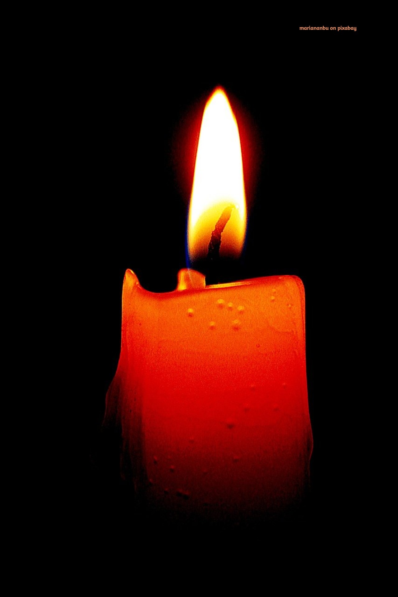 A single red candle burns steadily against a dark background. The flame glows with soft light, symbolizing love, presence, and strength within the fire. Love, the light, and fear, the dark, coexist.