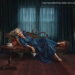 A beautiful, silver-haired woman swooning on her chaise lounge. Tea cup beside her on small table.